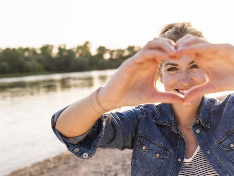 A smiling woman demonstrating heart shape using her hands