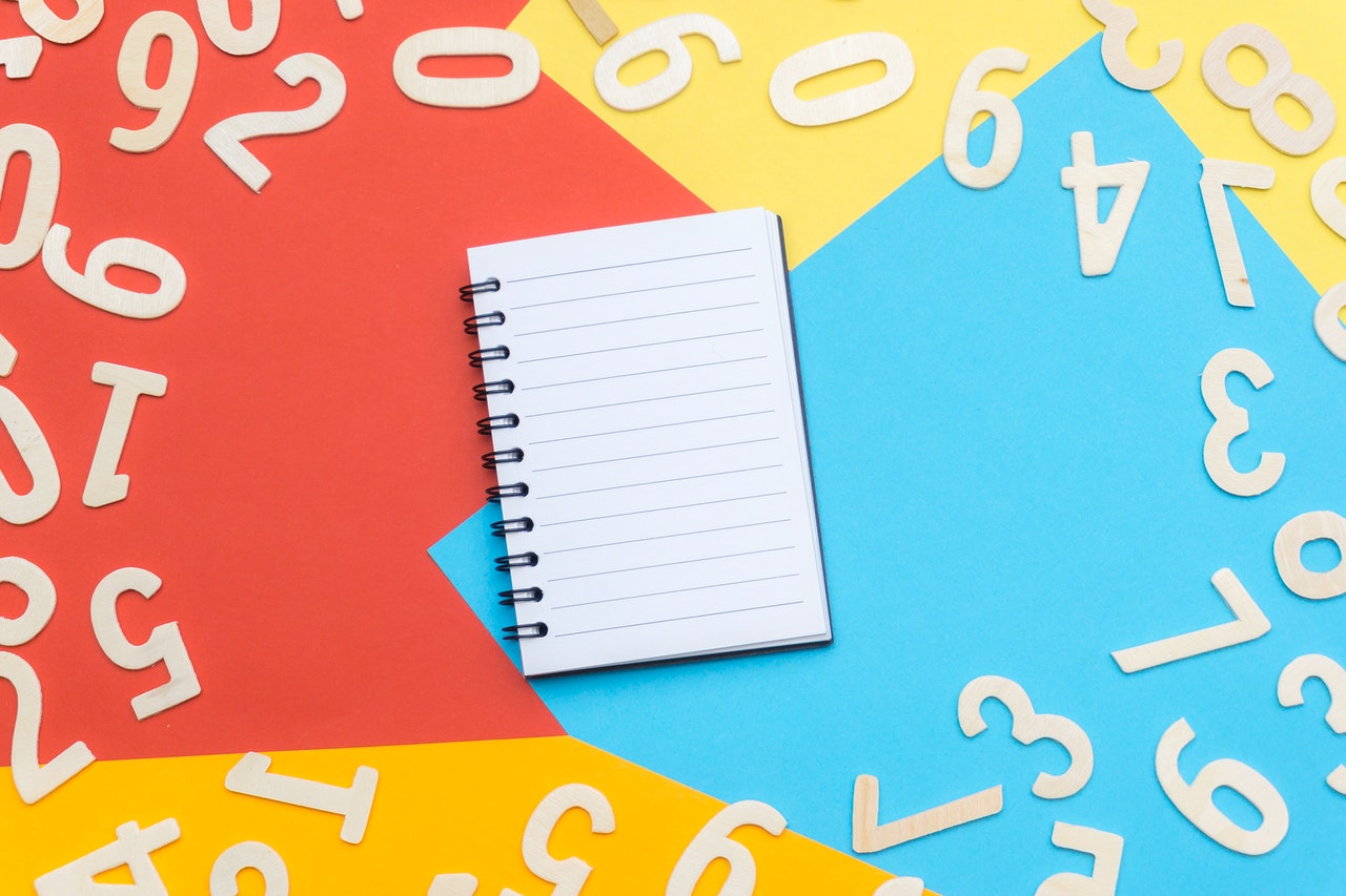 White Ruled Notebook with numbers all around it on different colored surface