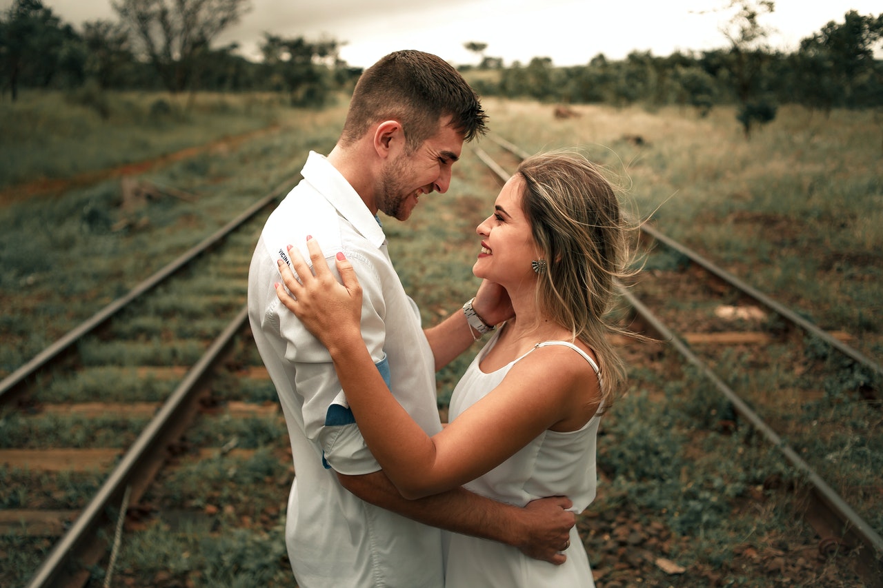 Smiling Man and Woman Facing Each Other Beside A Railway Train