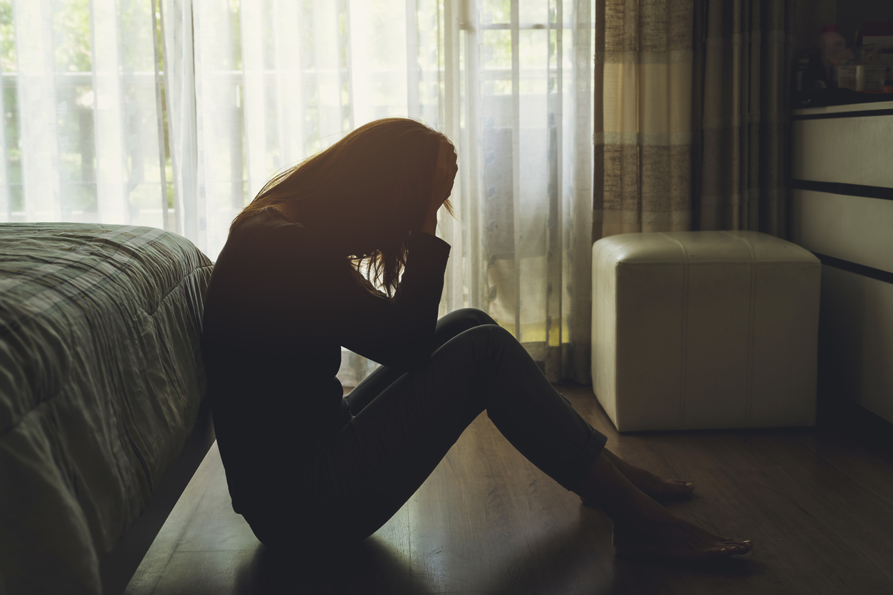 A woman sitting on the floor with her face down