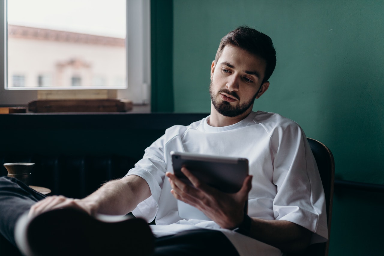 Man in White Shirt Holding an Ipad With Attitude