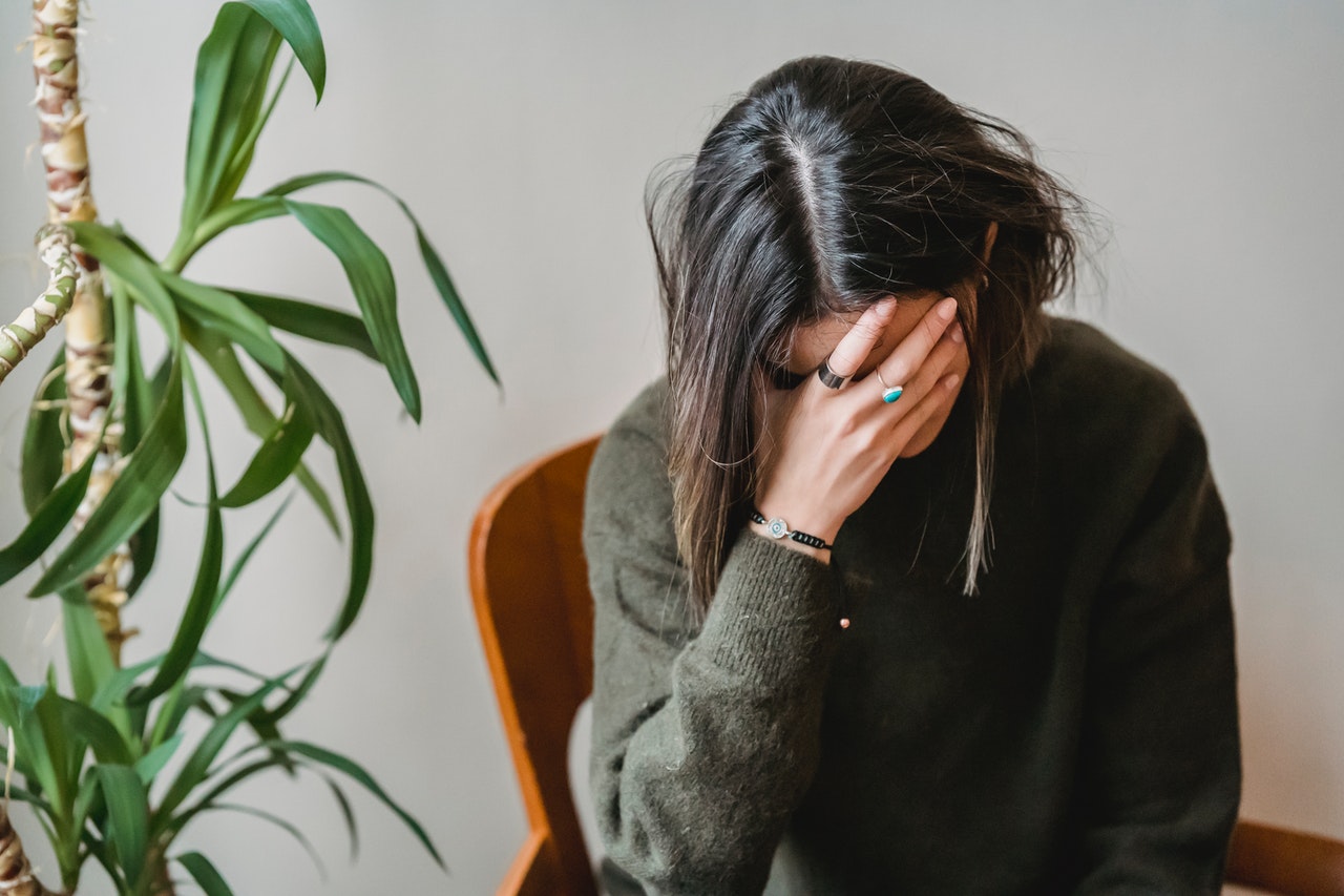 Worried young woman covering her face with her hand