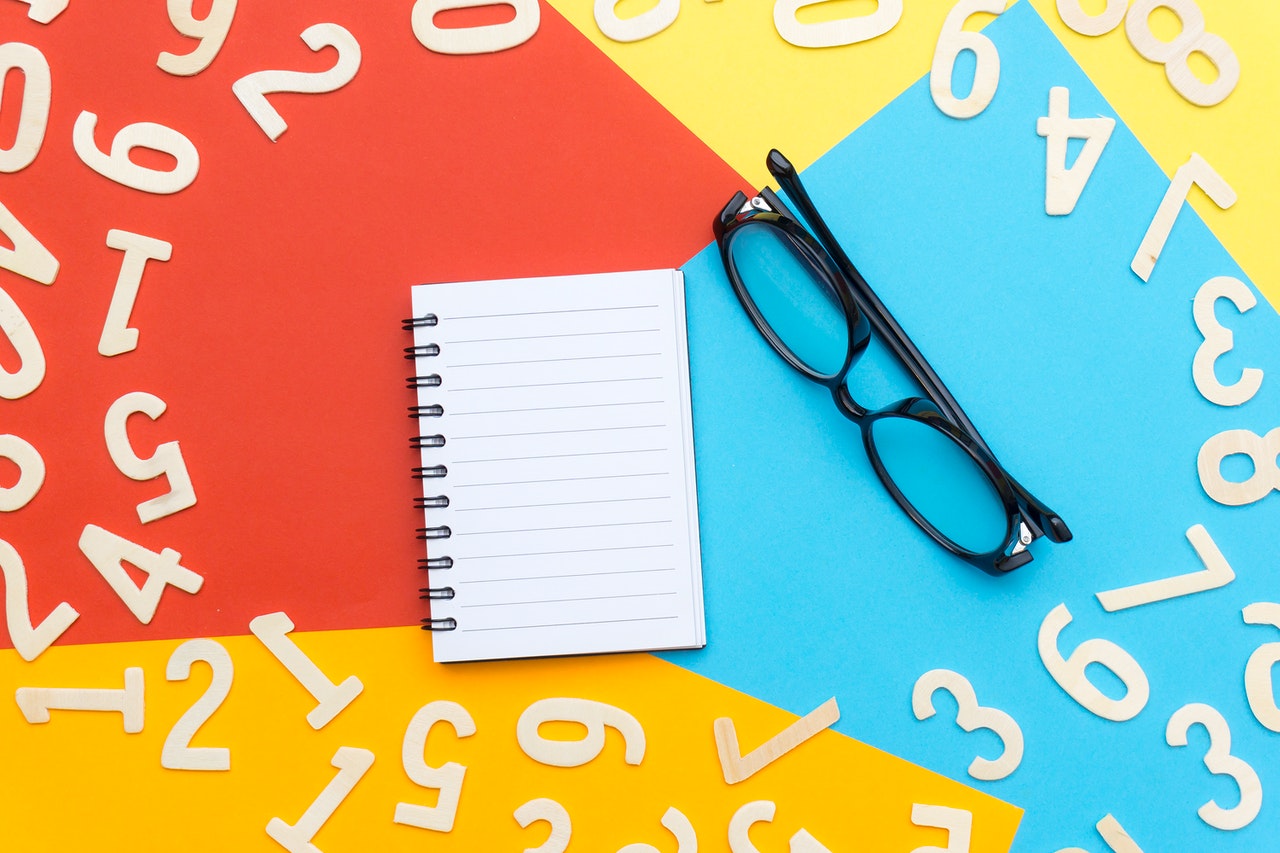 Black Framed Eyeglasses Beside Notebook with numbers all around it