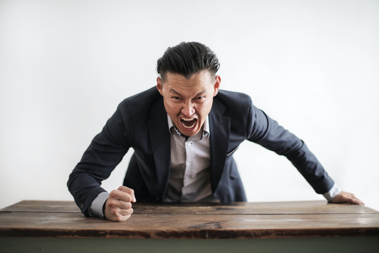 A man wearing a suit is yelling angrily at the camera