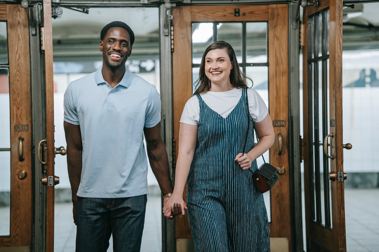 Couple Holding Hands While Walking Through Wooden Doors