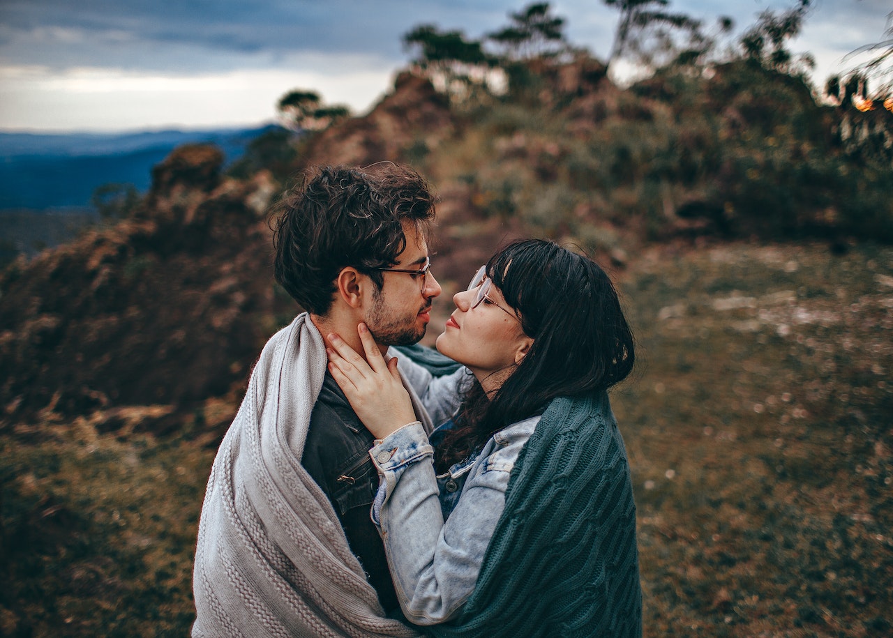 Woman Sharing Blanket With Man While Hugging And Looking At Each Other