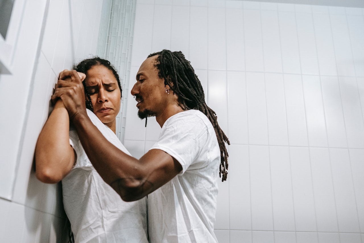 Aggressive man and frightened woman quarreling in bathroom