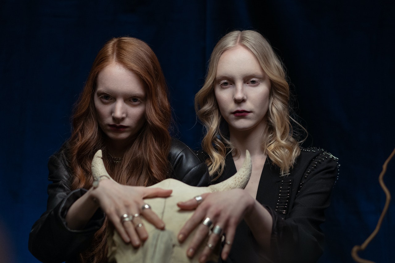 Two Women with Rings in Black Jackets Touching A Bull Skull