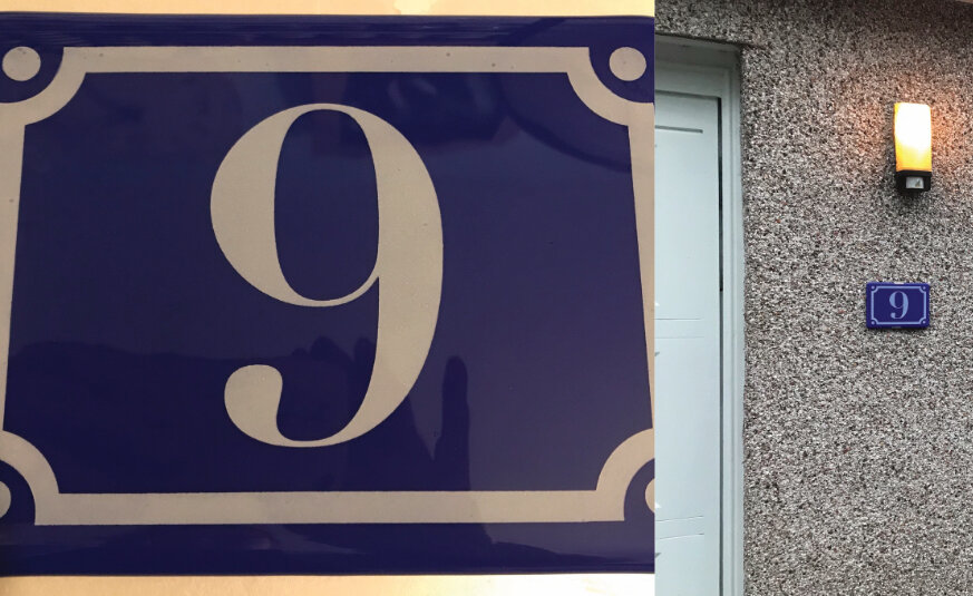 A wall with a blue marble plate having a number 9 on it