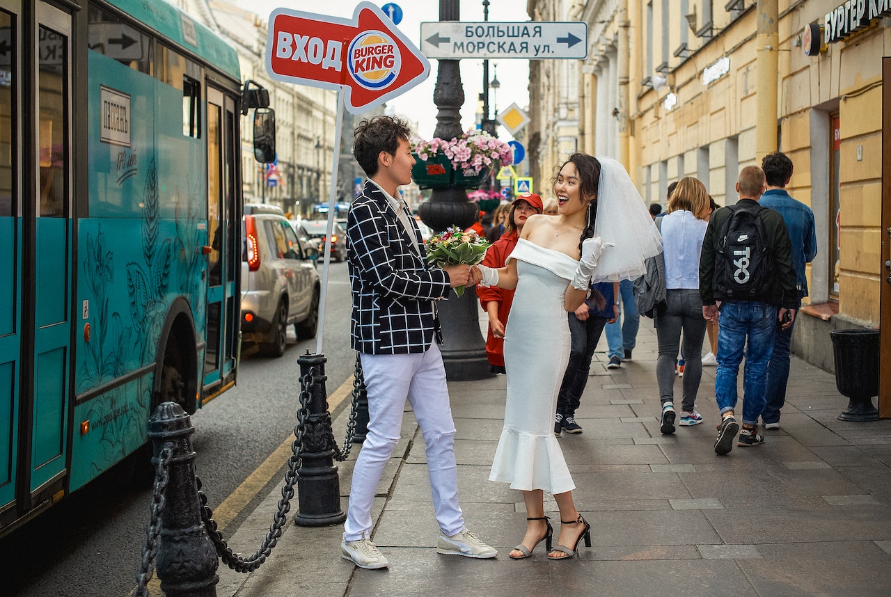 Man in Checkered Dress Shirt Holding Bouquet of Flowers with A Lady In A White Wedding Dress