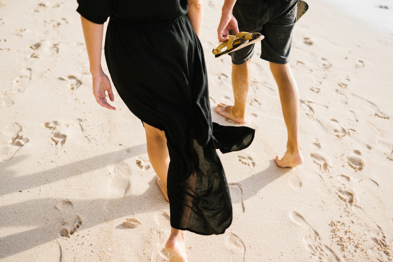 Two People Walking Barefoot on the Sand