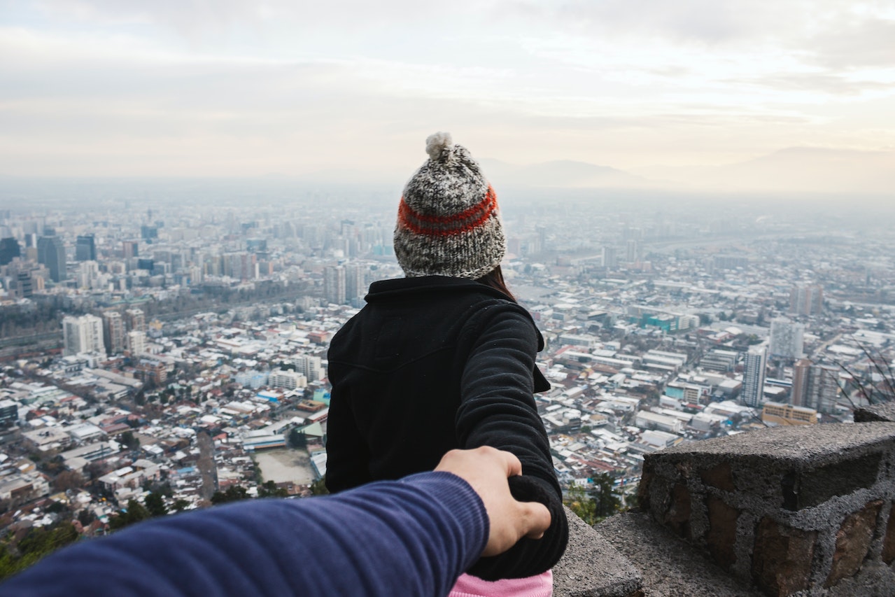 Man Holding Woman's Hand While She Looks At The City