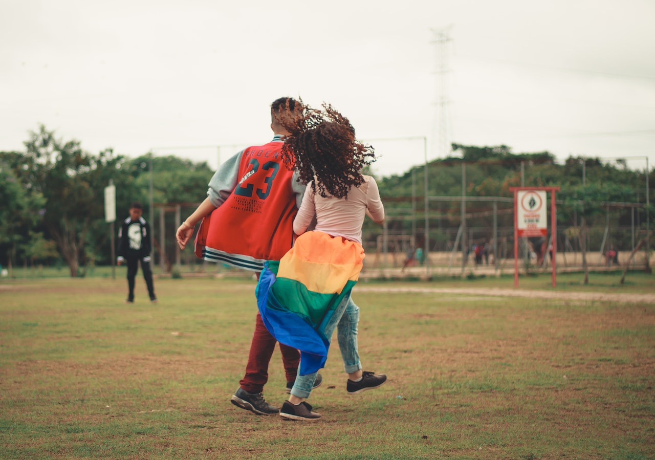 Man and Woman Walking on Green Grass Field