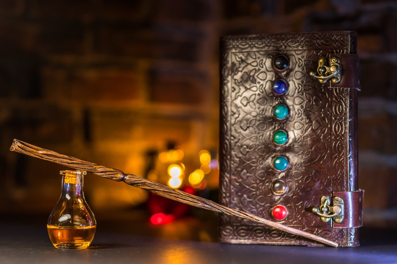 Potion and Wand beside a Spell Book