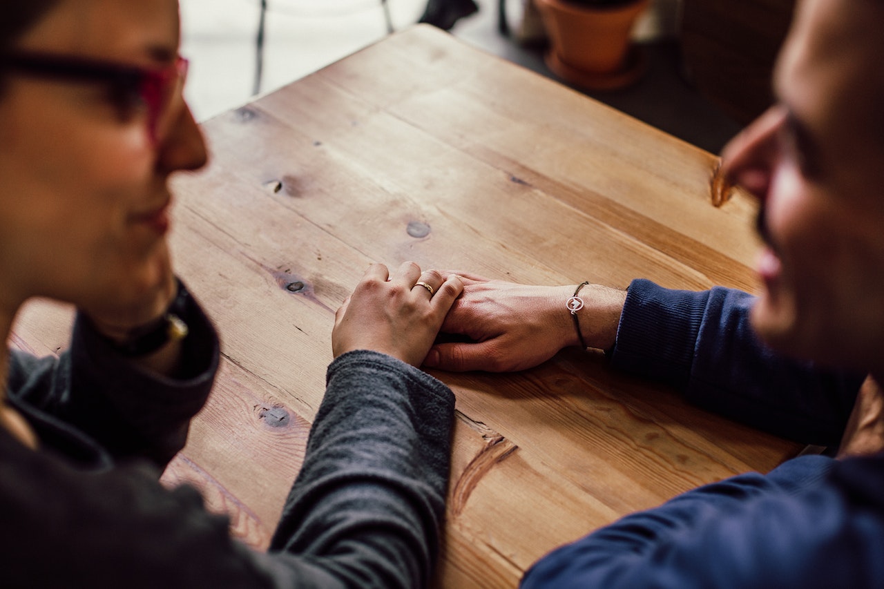 Man and Woman with Their Held Hands on a Table
