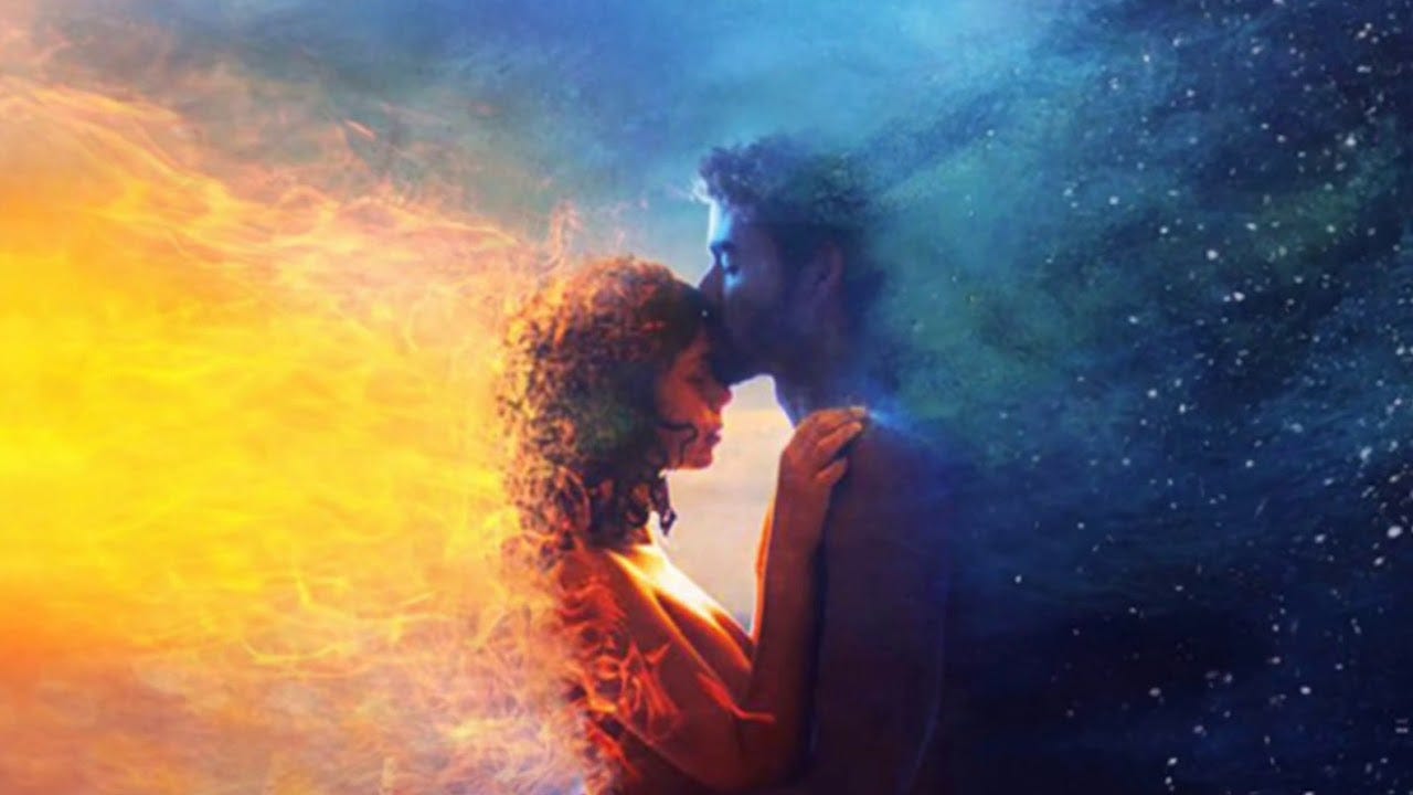 A man glowing in blue flames kissing a woman glowing in yellow flames on the forehead.